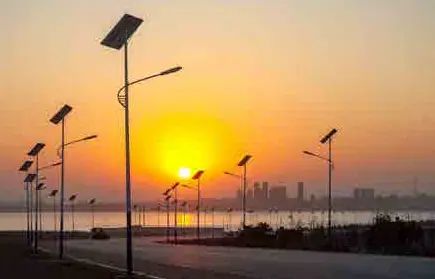 Solar LED street lights along a coastal road at sunset.
